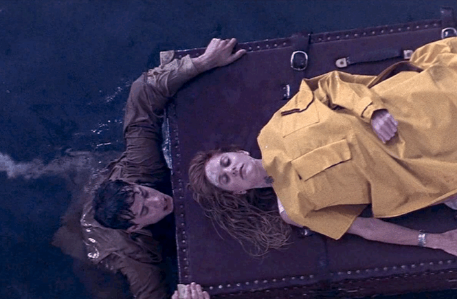 Patricia (Meg Ryan) lies unconscious on a steamer trunk adrift in the ocean as Joe (Tom Hanks) swims next to her, clinging to the trunk